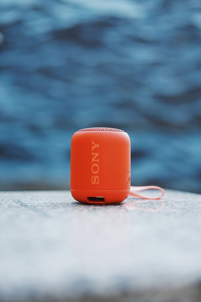 Home Compact red speaker against abstract blue background on marble top, ideal for tech themes.
