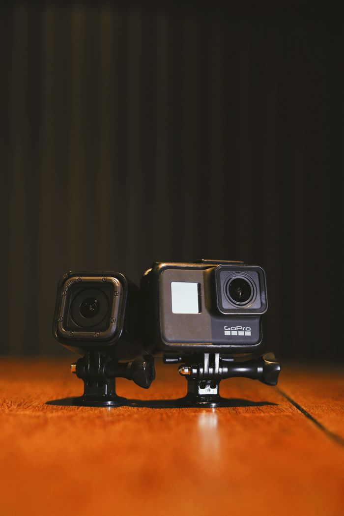 Services Two compact action cameras on a wooden surface against a dark background, showcasing modern technology.