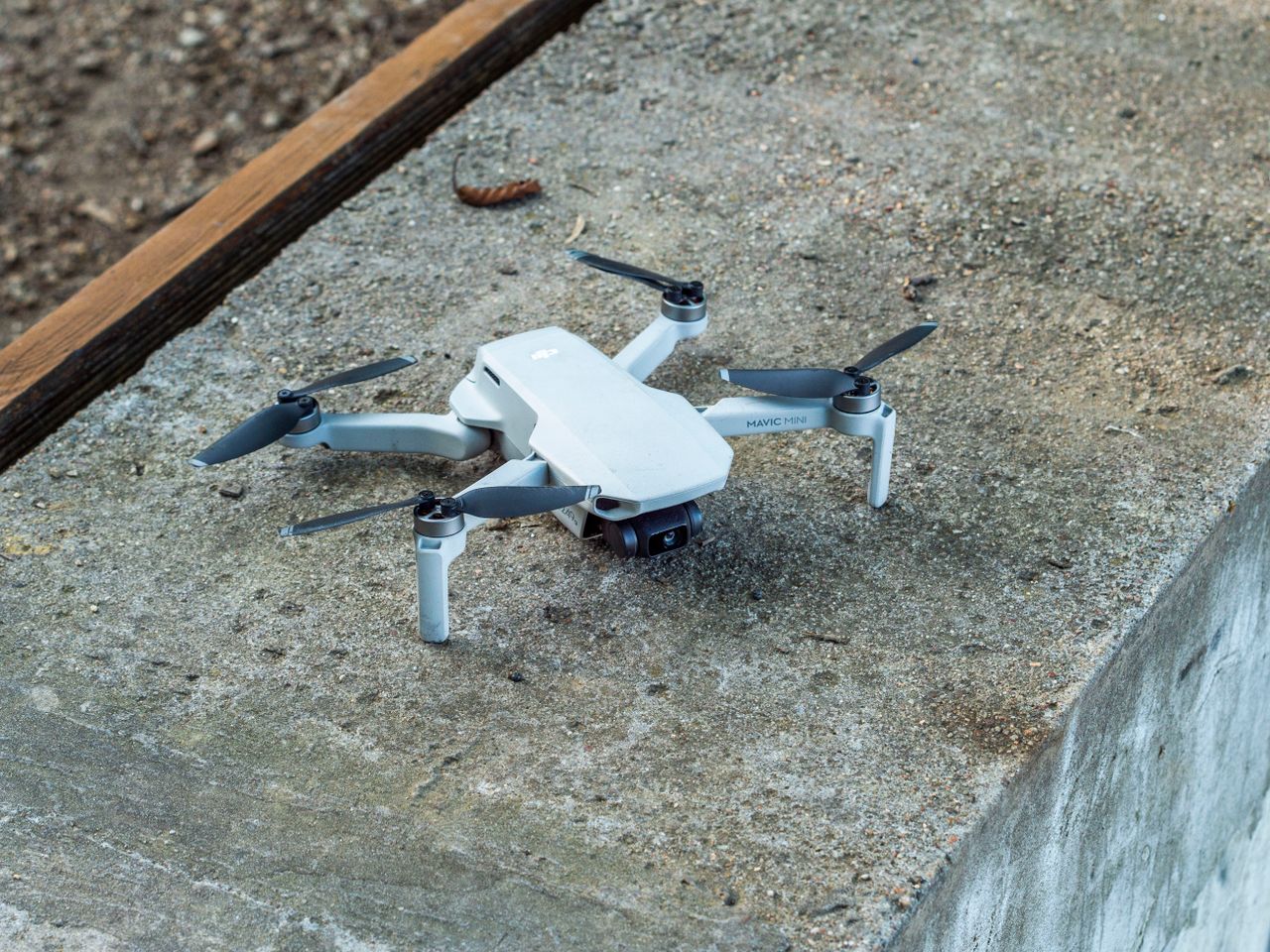 About A close-up image of a compact drone resting on a concrete surface.