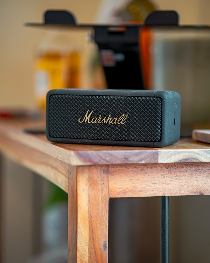 Services Compact Bluetooth speaker on a wooden table indoors, ideal for music and travel enthusiasts.