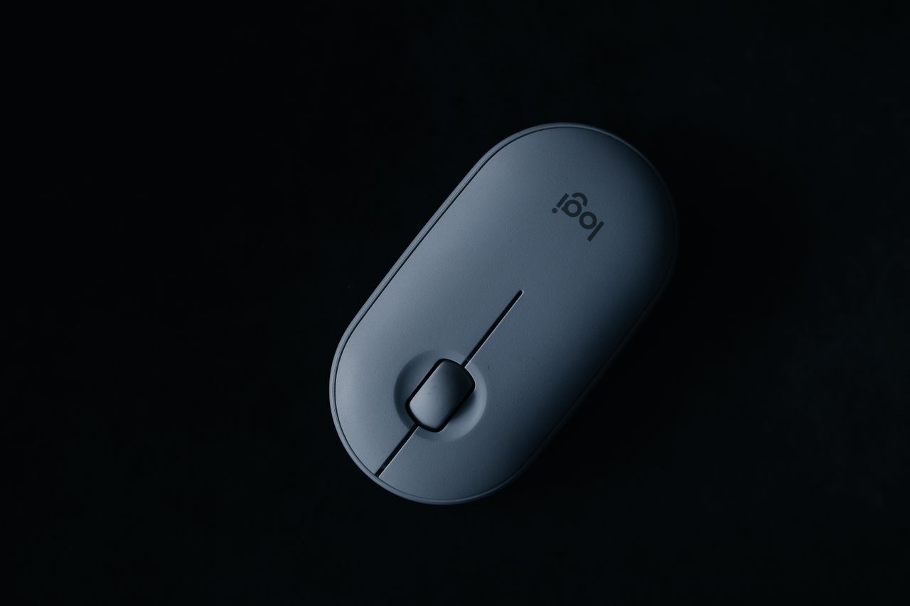 Home Sleek, modern wireless mouse displayed on a black background in an artistic flat lay.