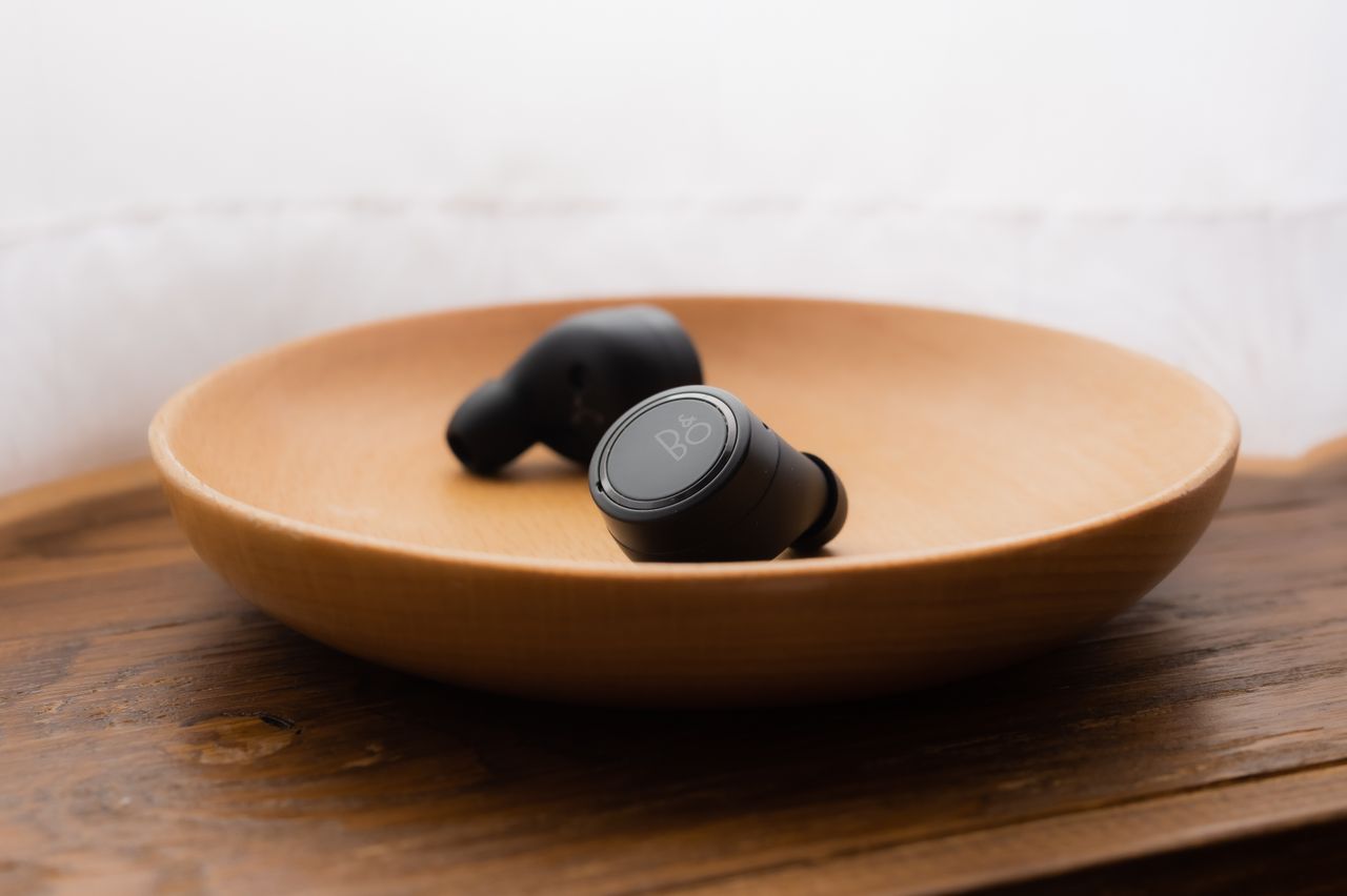 The Art of Drawing Readers In: Your attractive post title goes here Close-up of black wireless earbuds placed in a stylish wooden bowl on a wooden surface.
